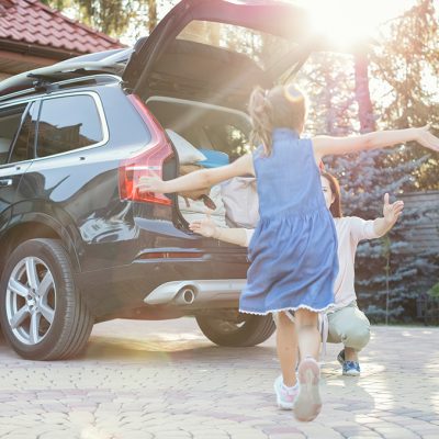 Mother and daughter embracing in front of their car